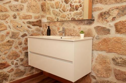 a bathroom with a white sink and a stone wall at Casa Da Belina : casa de ferias com piscina, Labruja, Ponte de Lima in Ponte de Lima