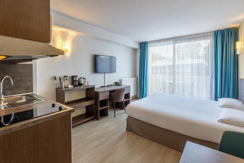 ein Hotelzimmer mit einem Bett und einer Küche in der Unterkunft Les Loges du Park in Aix-les-Bains