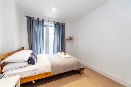 Schlafzimmer mit einem Bett und einem Fenster in der Unterkunft Spacious Modern 3 BR Apt w Balcony, Woolwich in Woolwich
