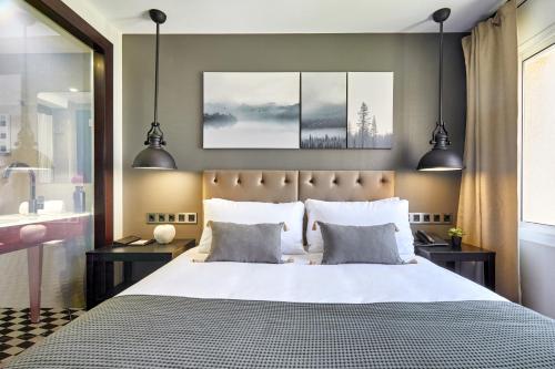 a bedroom with a large bed with two lamps at Hotel Cortes Rambla in Barcelona