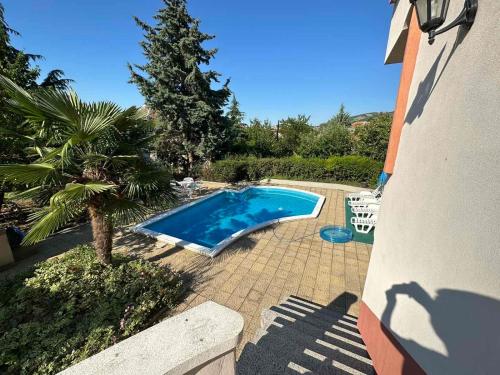 a swimming pool next to a house with a palm tree at Славина къща in Perushtitsa
