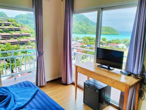 a bedroom with a desk with a television and a balcony at Blue View House Phi Phi in Phi Phi Don
