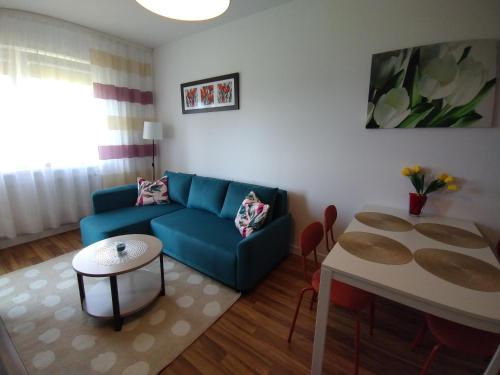 a living room with a blue couch and a table at Apartament Gardena Olsztyn Jaroty in Olsztyn