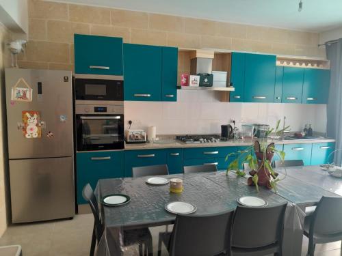 a kitchen with blue cabinets and a table with chairs at Ta Naqċil in Xagħra