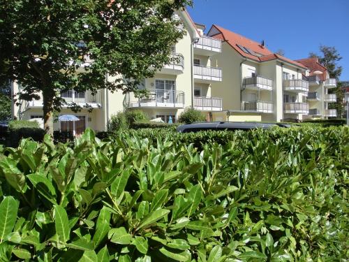 un immeuble d'appartements avec une haie en face dans l'établissement Ferienwohnung H16 "Strandkorb", à Graal-Müritz