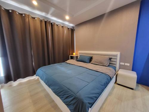 a bedroom with a bed with blue sheets and a curtain at The patio condo Bang saen in Ban Bang Saen (1)
