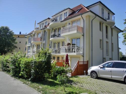 uma casa branca com um carro estacionado em frente dela em Ferienwohnung i20 em Graal-Müritz