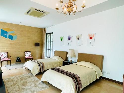 a bedroom with two beds and a chandelier at Baan Ing Khao in Pak Chong