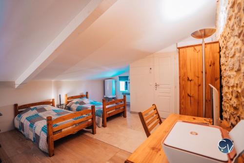 1 Schlafzimmer mit 2 Betten, einem Schreibtisch und einem Tisch in der Unterkunft Agréable maison de village avec terrasse in Pougnadoresse