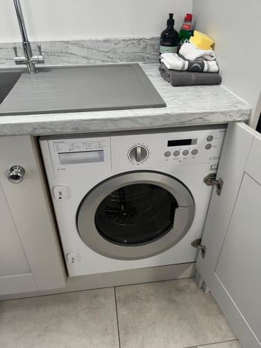 a white washing machine in a kitchen with a counter at The Apartment Cold Comfort Farm in Hinckley