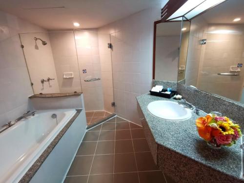 a bathroom with a tub and a sink and a mirror at Duangtawan Hotel Chiang Mai -SHA Extra Plus in Chiang Mai