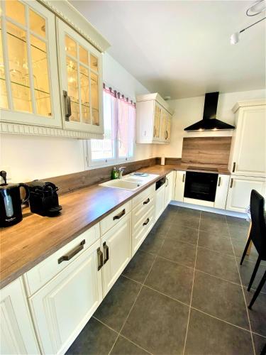 une cuisine avec des armoires blanches et un plancher en bois dans l'établissement GITE CESAR 6p, 3ch, piscine privée, terrain privé clos, terrain de pétanque, à Vallon-Pont-dʼArc