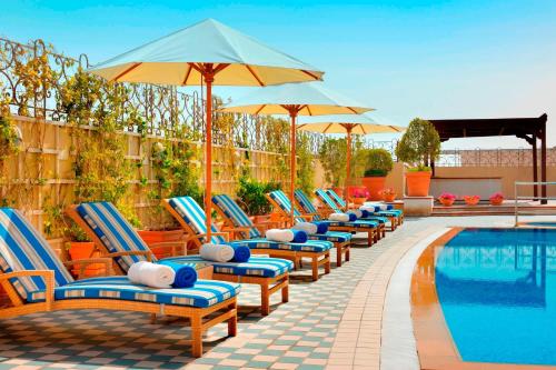 een rij stoelen en parasols naast een zwembad bij Marriott Executive Apartments Dubai Creek in Dubai
