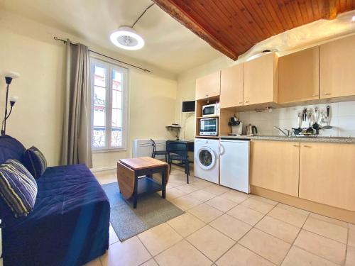 een woonkamer met een blauwe bank en een keuken bij Le Grand Pré By SCLS Locations in Cannes