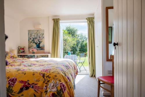 Un dormitorio con una cama con un edredón colorido y una ventana en The Potting Shed, en Woodstock