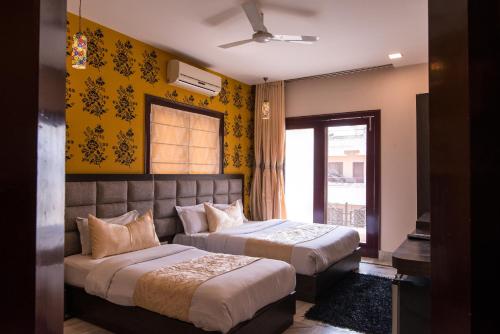 2 Betten in einem Zimmer mit gelben Wänden in der Unterkunft Hotel Buddha in Varanasi