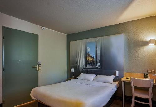 a bedroom with a bed and a table and a chair at B&B HOTEL AVRANCHES Baie du Mont St-Michel in Le Val-Saint-Père