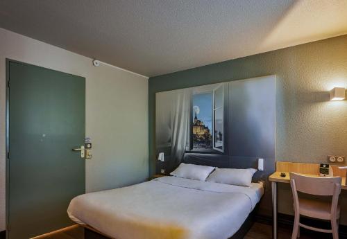 ル・ヴァル・サン・ペールにあるB&B HOTEL AVRANCHES Baie du Mont St-Michelのベッドルーム1室(ベッド1台、テーブル、椅子付)