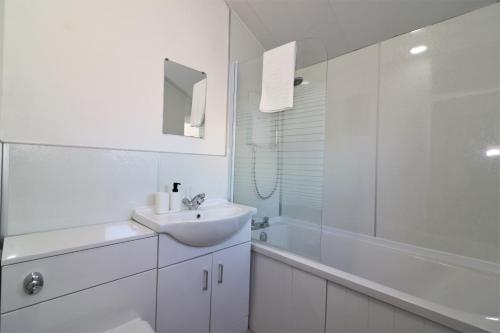 a white bathroom with a sink and a shower at Signature - Alder View in Cumbernauld