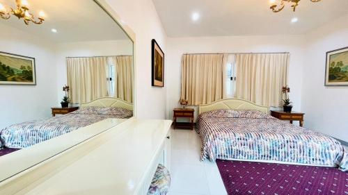 two beds in a room with a mirror at Baan Ing Khao in Pak Chong