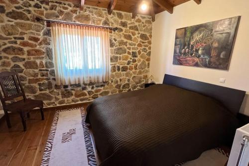a bedroom with a bed and a stone wall at Mountain View - Full Villa in Polydrossos