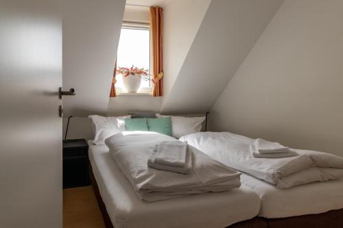 a bedroom with a bed with white sheets and a window at Postwiese in Winterberg