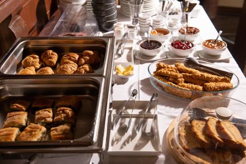 una tavola ricoperta di vassoi di prodotti da forno e altri alimenti di Natura Chalets a Megalo Chorio