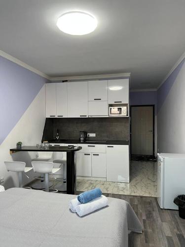 een keuken met witte kasten en een bed in een kamer bij ITB Apartments Молодёжный in Alma-Ata