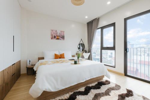 a white bedroom with a large bed and a large window at Myrcella Urban Studio in Hanoi