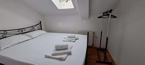 Un dormitorio con una cama blanca con toallas. en Apartman LaVista en Belgrado