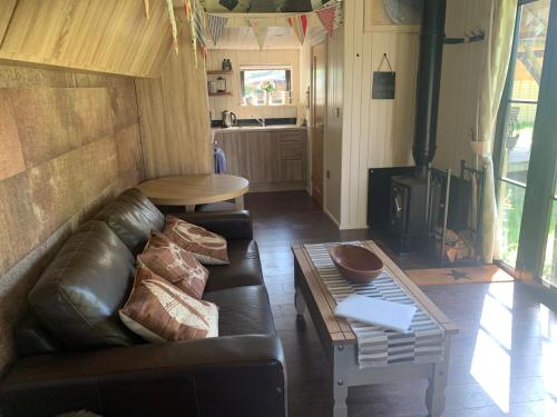 a living room with a couch and a wood stove at Oak Tree Lodge: Unique 2 level Shepherd's Hut: Dartmouth in Dartmouth