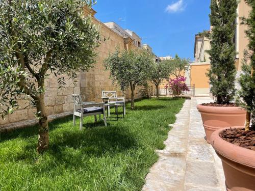 a garden with two chairs and trees in the grass at Palazzo Pitagora in Taranto