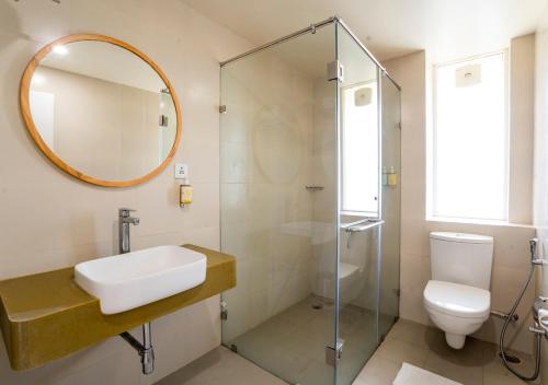 La salle de bains est pourvue d'un lavabo, de toilettes et d'un miroir. dans l'établissement Bloom Hotel - Jammu, à Jammu