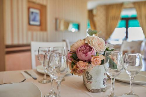 a table with a vase of flowers and wine glasses at Pensiunea Diamant in Ghimbav