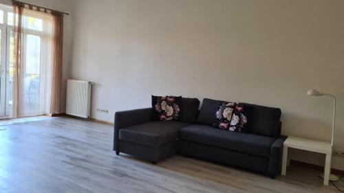 - un salon avec un canapé noir et une fenêtre dans l'établissement Spacious Condo 5 min to Jurmala Beach, à Jurmala