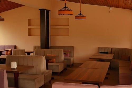 a dining room with tables and couches and lamps at Golden Fleece Hotel in Ureki