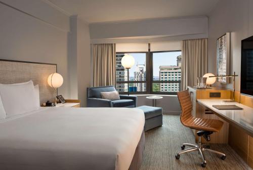 una camera d'albergo con un grande letto e una scrivania di New York Hilton Midtown a New York