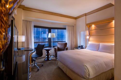 a hotel room with a bed and a desk and a window at New York Hilton Midtown in New York