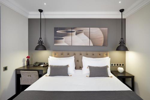 a bedroom with a white bed and a desk at Hotel Cortes Rambla in Barcelona