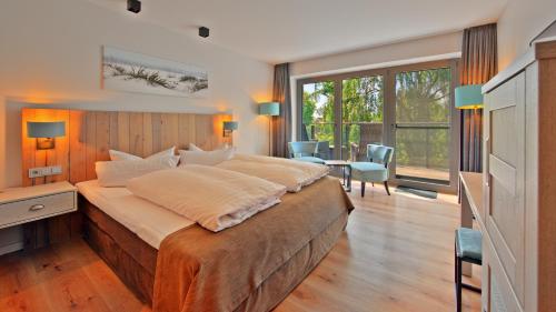 a large bedroom with a large bed and a desk at Elbstrand Resort Krautsand - Hotel Elbstrand in Drochtersen