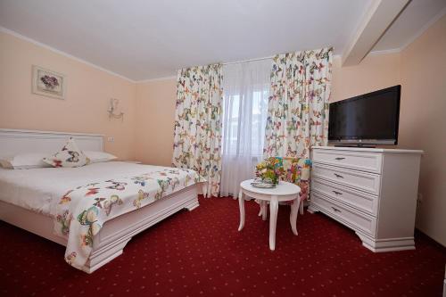 a bedroom with a bed and a flat screen tv at Pensiunea Diamant in Ghimbav