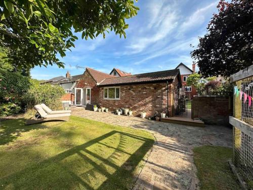 a brick house with a white couch in the yard at Leafy lodge in Lytham in Brown Moss Side