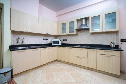 a kitchen with wooden cabinets and a microwave at SS Mystic Apartotel in Bangalore