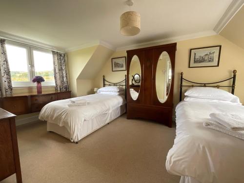 a bedroom with two beds and a mirror at Blaeberry Cottage in Killean