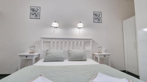 a white bedroom with a bed and two night stands at Finnem Rentals Jičínská in Prague