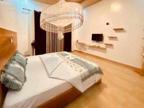 um quarto com uma cama grande e um lustre em BIZI HOMES, KABUGA 