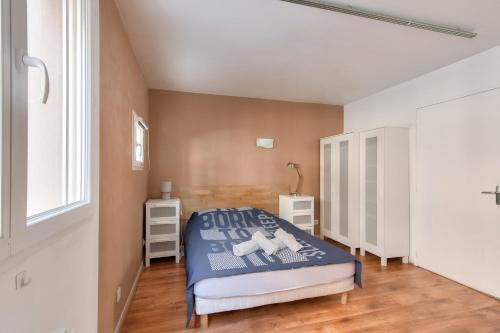 een slaapkamer met een blauw bed en een raam bij Cosy studio à proximité du Parc Sergent Blandan in Lyon