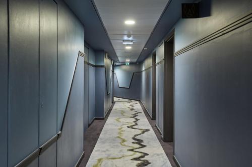 a hallway with blue walls and a long aisle at voco Paris - Porte de Clichy by IHG in Clichy