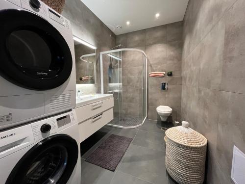 a bathroom with a washer and dryer next to a shower at Jaw dropping New Penthouse apt in Svolvær in Svolvær