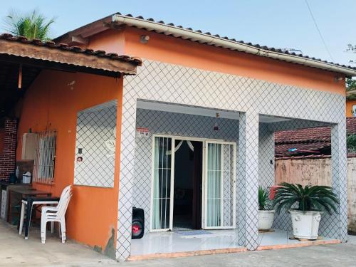 uma casa laranja e branca com uma mesa e cadeiras em Casa espaçosa com Piscina e Churrasqueira 2 dorm no Guarujá